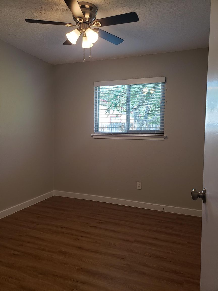 802 Ranch Road, Unit A Georgetown, TX 78628 - Photo 8 of 11 A comfortable bedroom features a ceiling fan, window with blinds, and rich wood flooring.