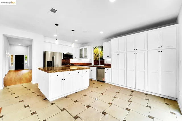 a large white kitchen with white cabinets and stainless steel appliances