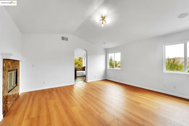 a view of an empty room with window and wooden floor