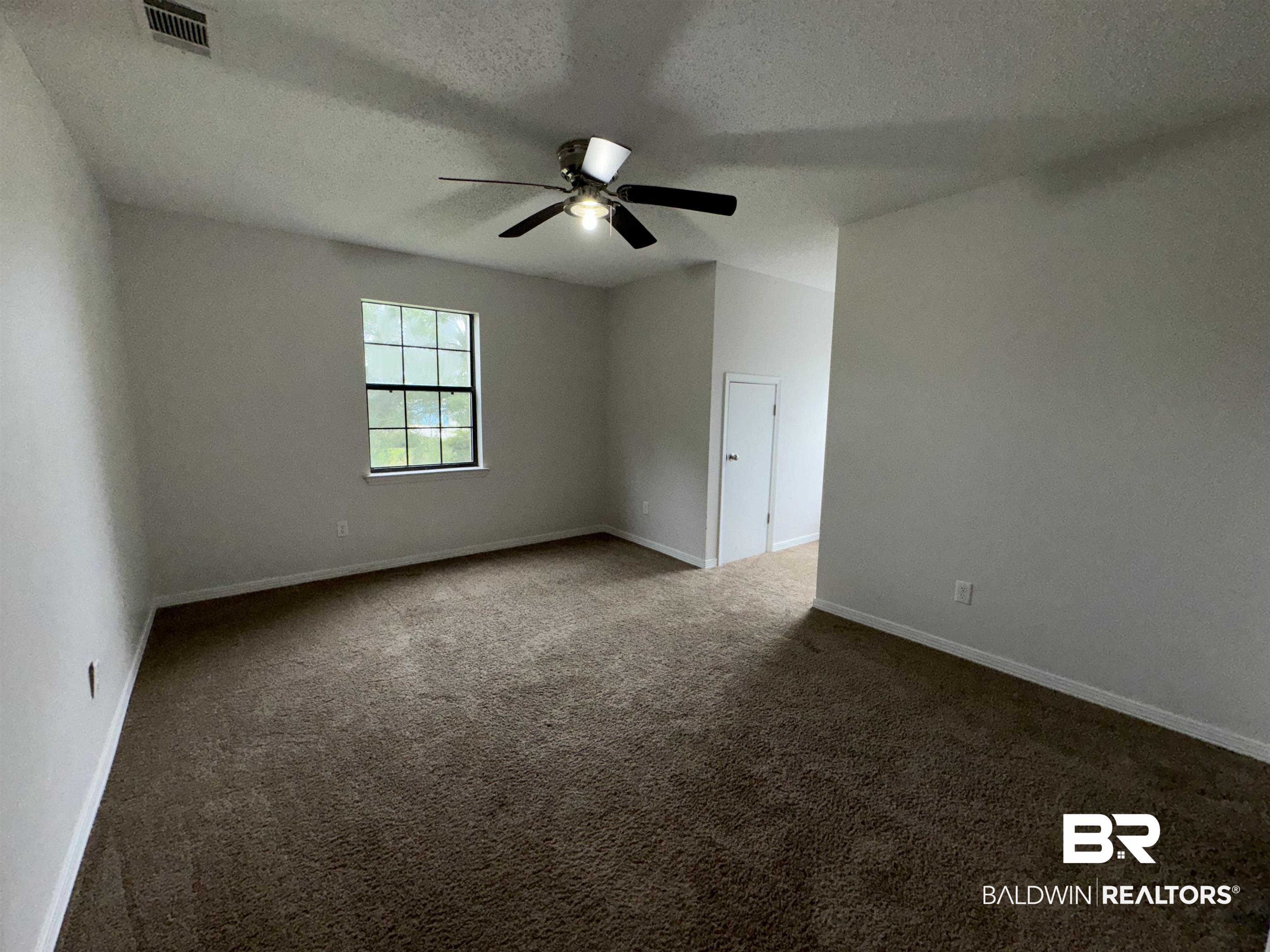 70 Plum Street Uriah, AL 36480 - Photo 23 of 36 Unfurnished room featuring dark colored carpet, a textured ceiling, vaulted ceiling, and ceiling fan
