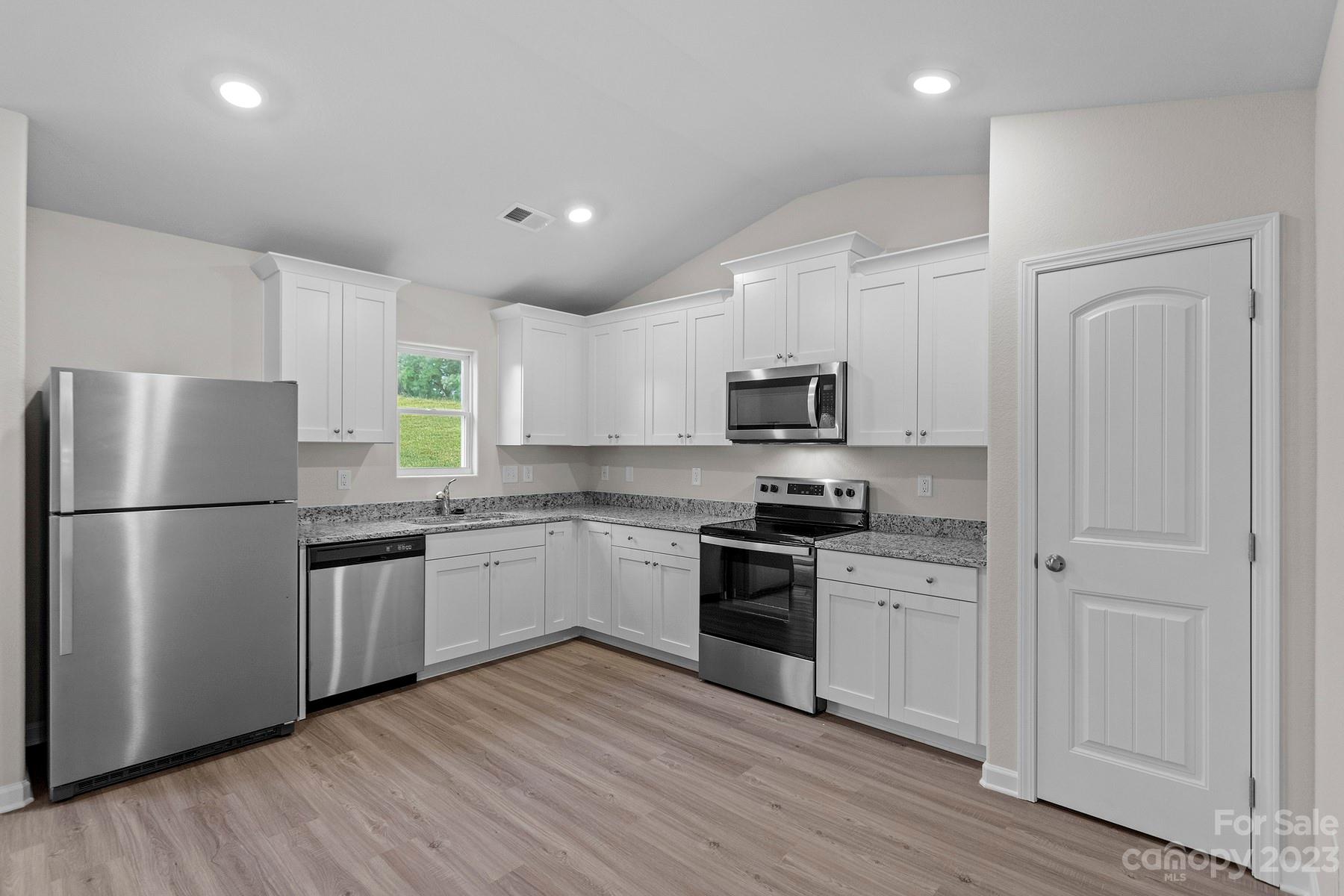 1716 Nia Road Charlotte, NC 28215 - Photo 3 of 10 a kitchen with a refrigerator a stove top oven a sink and dishwasher with wooden floor