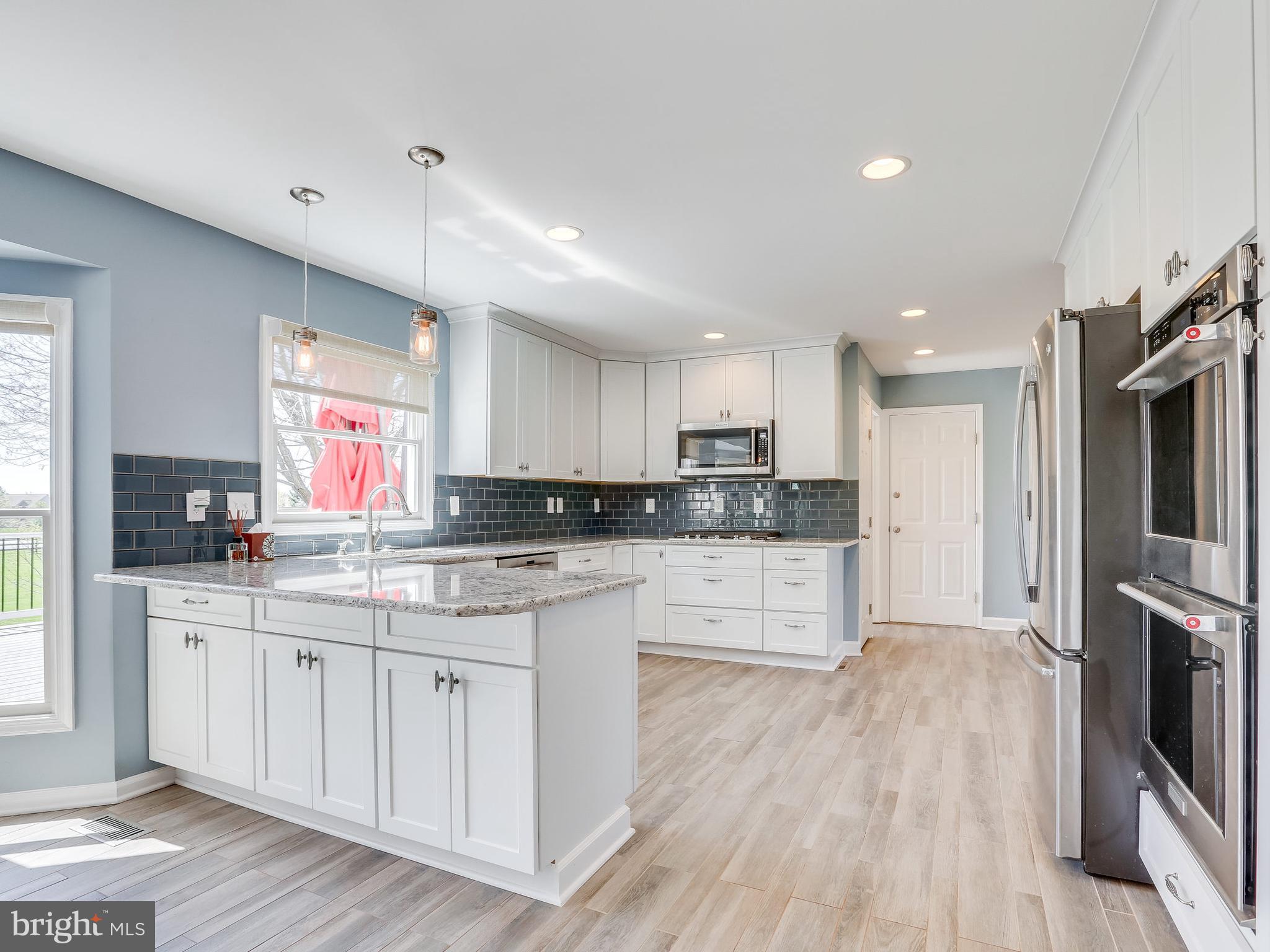 16910 Hoskinson Road Poolesville, MD 20837 - Photo 2 of 30 a large kitchen with stainless steel appliances kitchen island granite countertop a stove a sink a refrigerator and white cabinets with wooden floor
