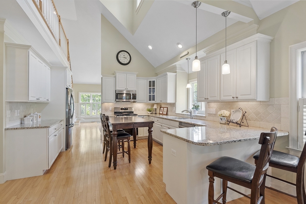 22 Hummock Way, Unit 22 Hudson, MA 01749 - Photo 6 of 23 a kitchen with kitchen island granite countertop a table chairs sink and cabinets
