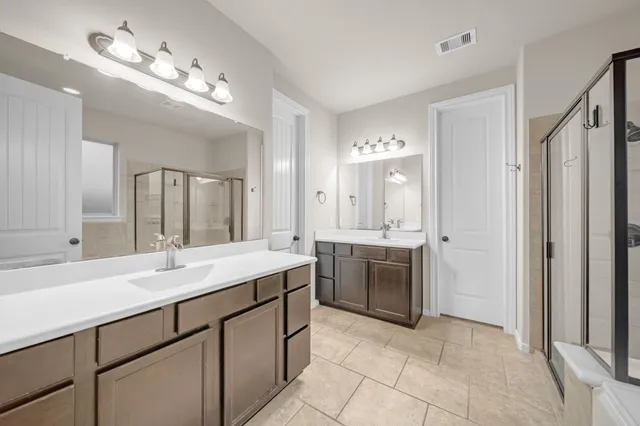 a spacious bathroom with a double vanity sink a mirror a bathtub and