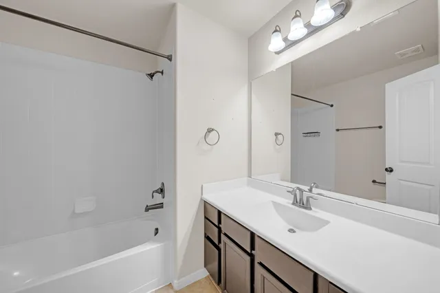 a bathroom with a sink double vanity granite tub shower and a mirror