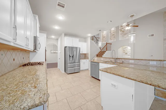 a kitchen with stainless steel appliances granite countertop a sink a stove and a refrigerator