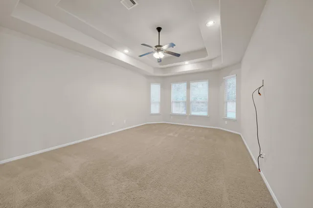 an empty room with chandelier fan and windows