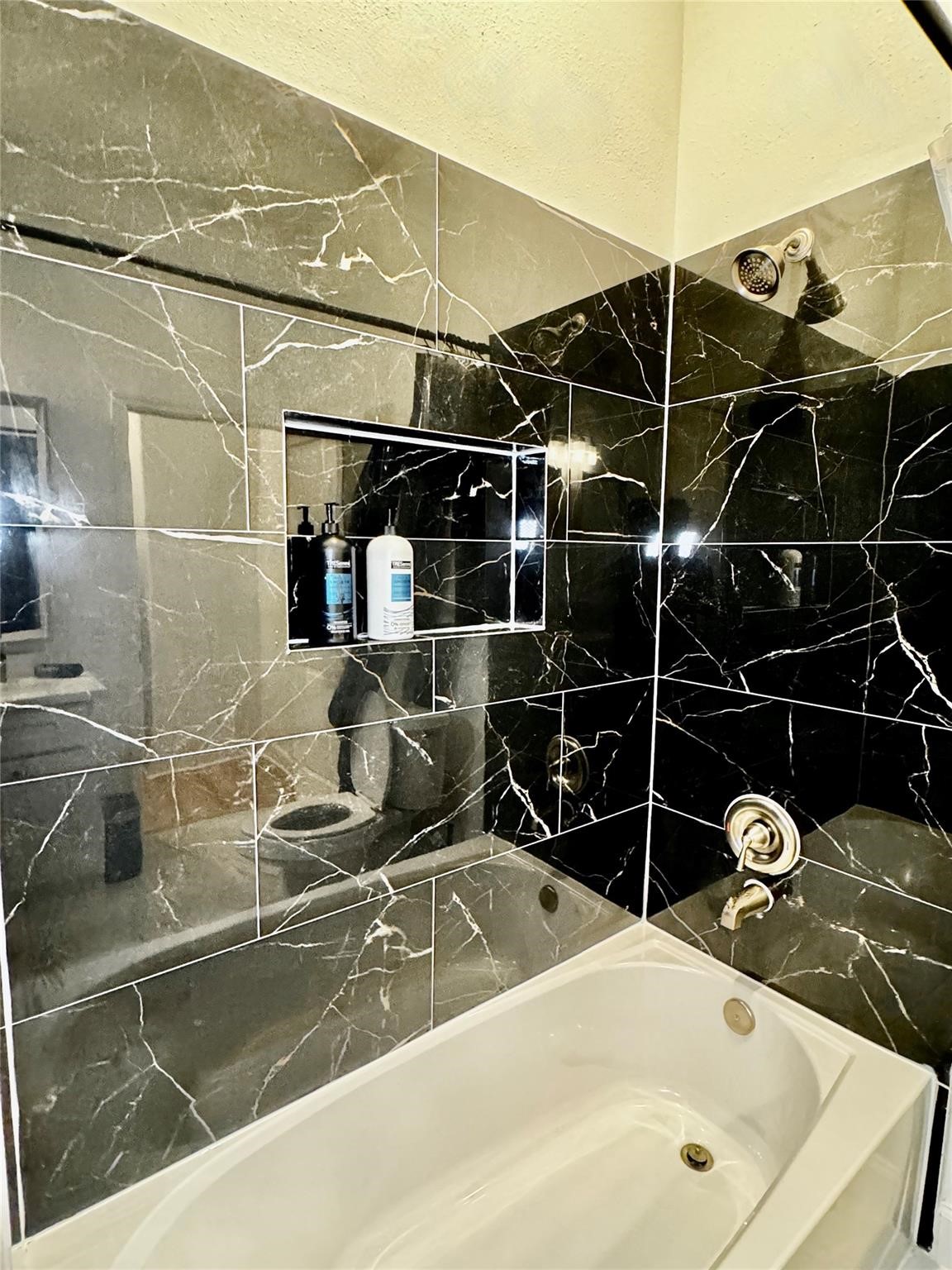 5306 Ridgeway Drive, Unit A Houston, TX 77033 - Photo 10 of 14 Tub & Shower – Tub and shower combination surrounded by striking marble-look tile, complete with a built-in niche for convenient bath storage.