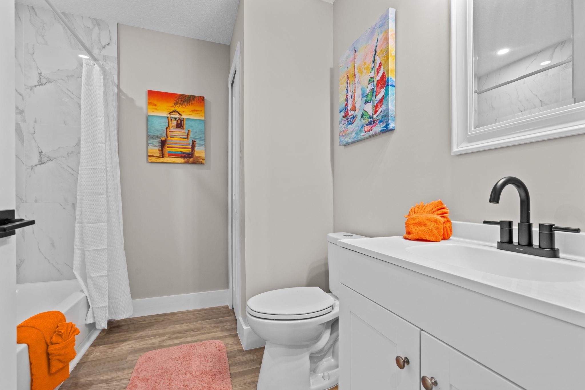 812 West 9th Street St. Augustine, FL 32084 - Photo 10 of 31 Bathroom featuring vanity, light wood-style floors, and a combined bath / shower with marble appearance