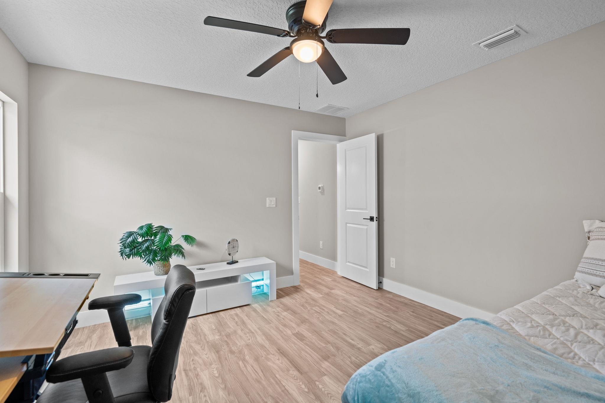 812 West 9th Street St. Augustine, FL 32084 - Photo 18 of 31 Bedroom featuring an office area, light wood finished floors, a textured ceiling, and a ceiling fan