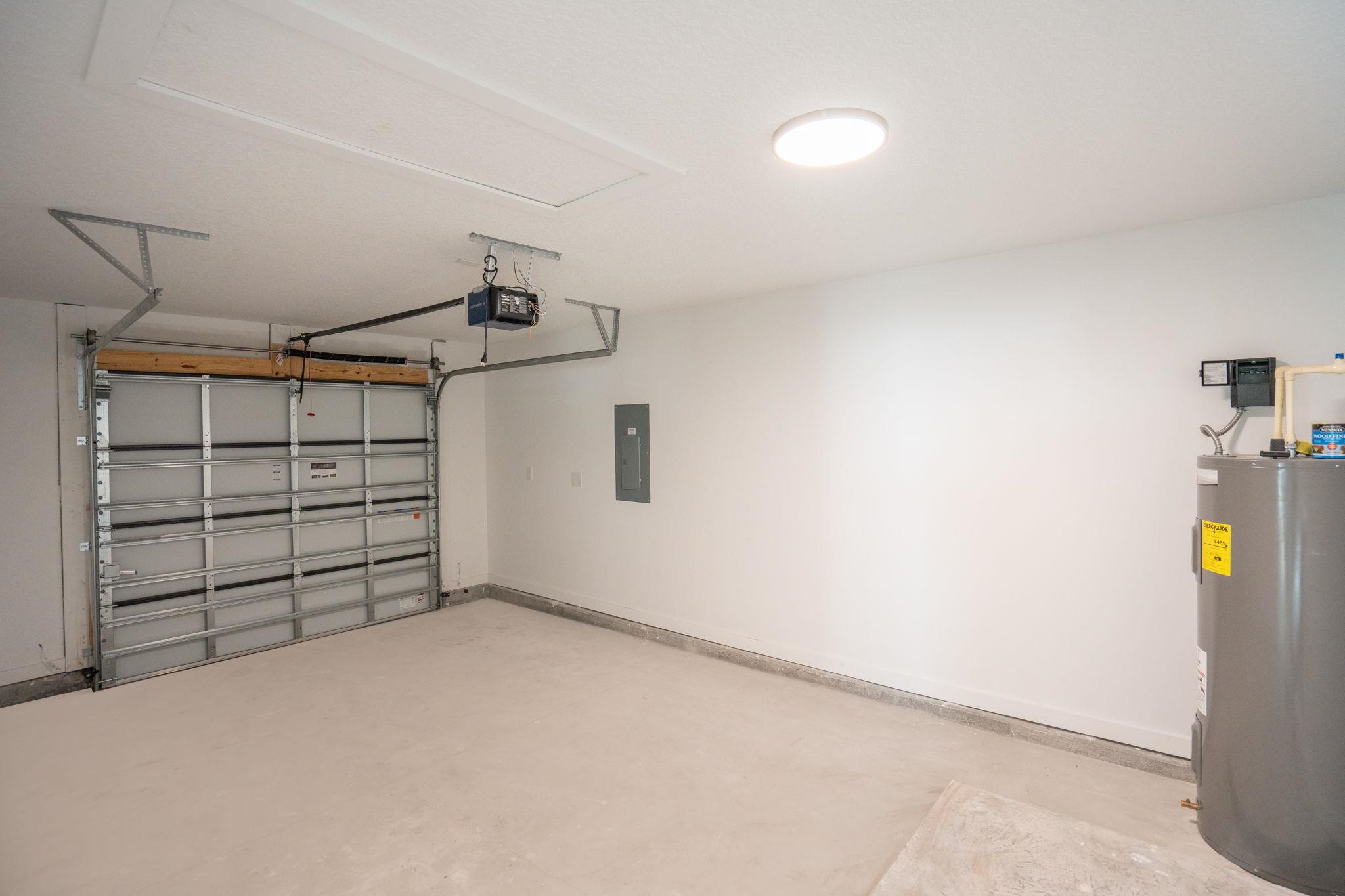 812 West 9th Street St. Augustine, FL 32084 - Photo 28 of 31 Garage featuring water heater, electric panel, and a garage door opener