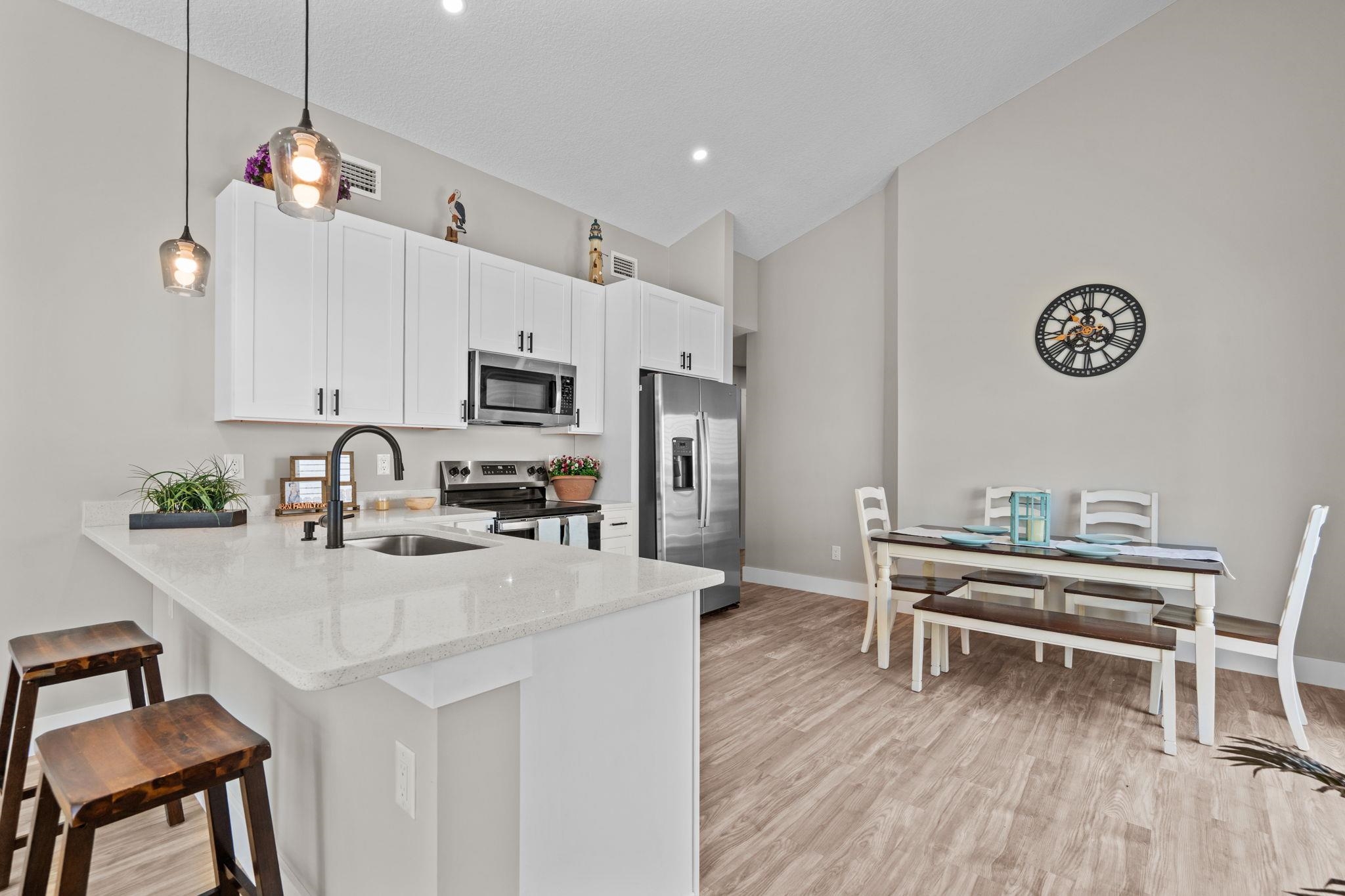 812 West 9th Street St. Augustine, FL 32084 - Photo 5 of 31 Kitchen with light stone counters, appliances with stainless steel finishes, decorative light fixtures, a kitchen breakfast bar, and white cabinets