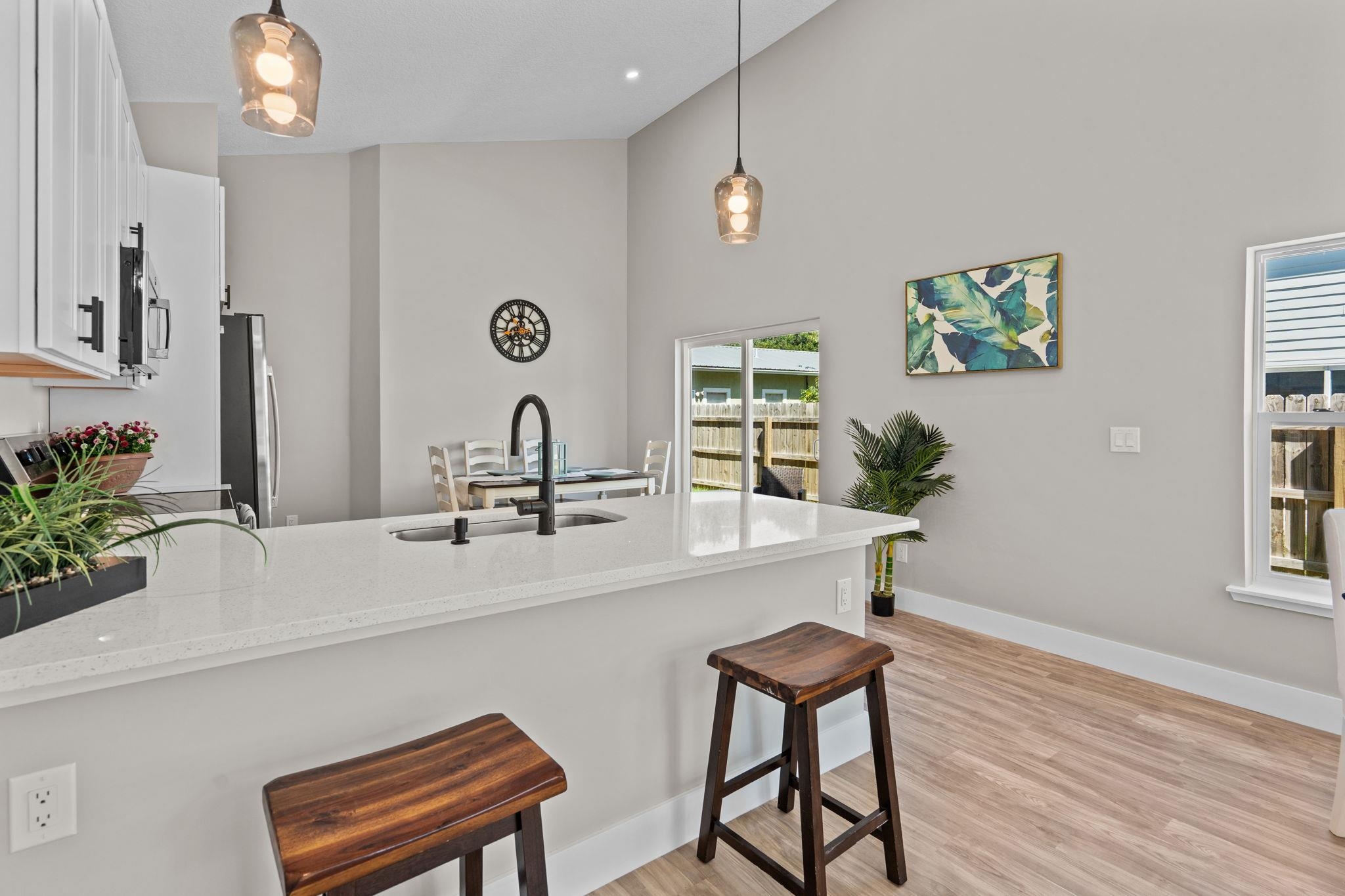 812 West 9th Street St. Augustine, FL 32084 - Photo 6 of 31 Kitchen featuring a kitchen bar, a peninsula, light stone countertops, white cabinets, and hanging light fixtures