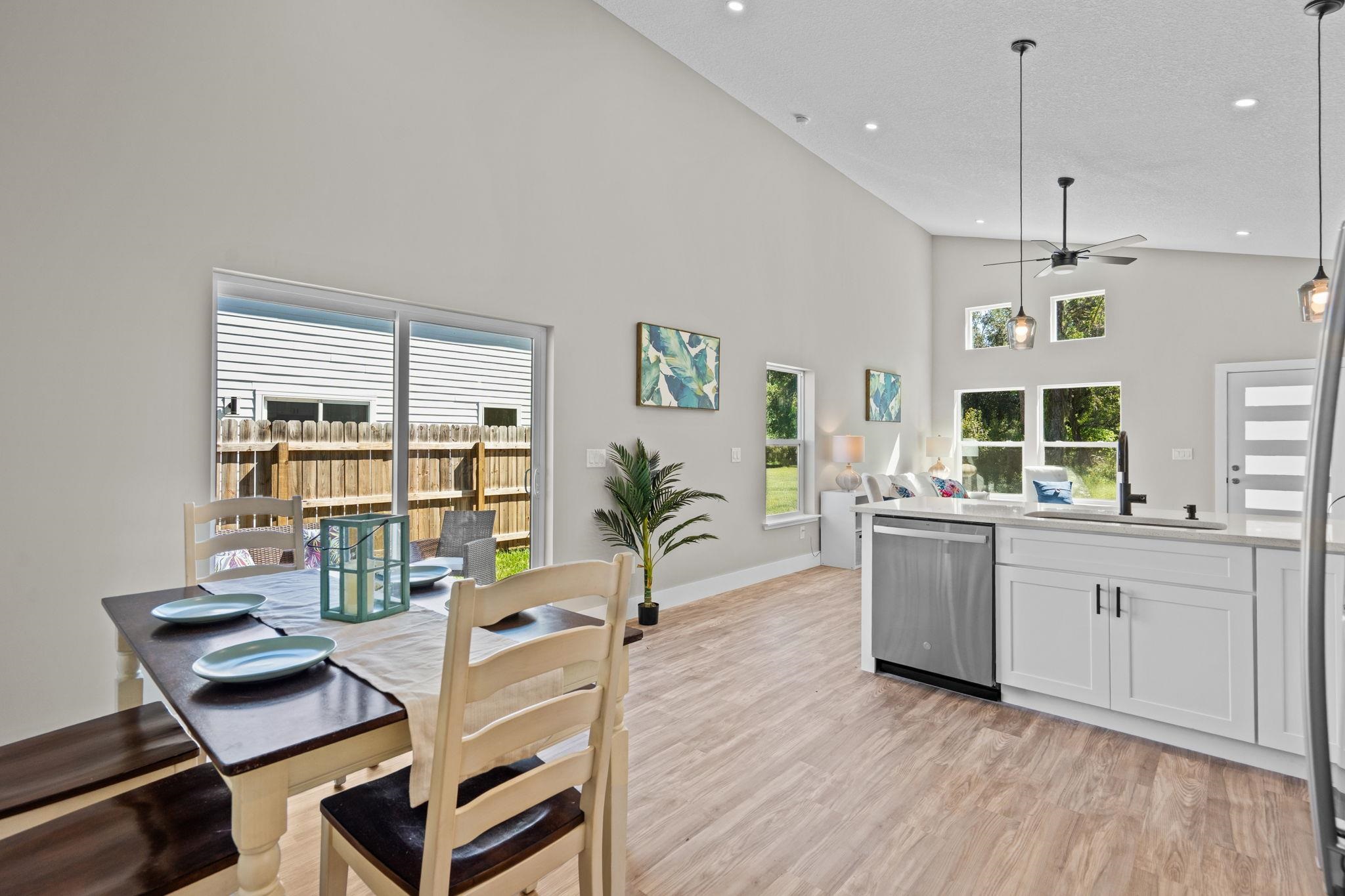 812 West 9th Street St. Augustine, FL 32084 - Photo 30 of 31 Kitchen with hanging light fixtures, stainless steel dishwasher, white cabinets, open floor plan, and a high ceiling