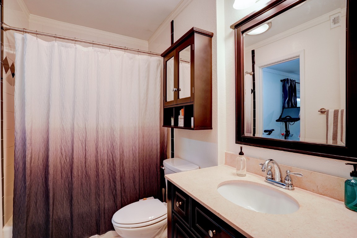 7920 Rockwood Lane, Unit 128 Austin, TX 78757 - Photo 17 of 36 a bathroom with a sink a toilet and shower curtain