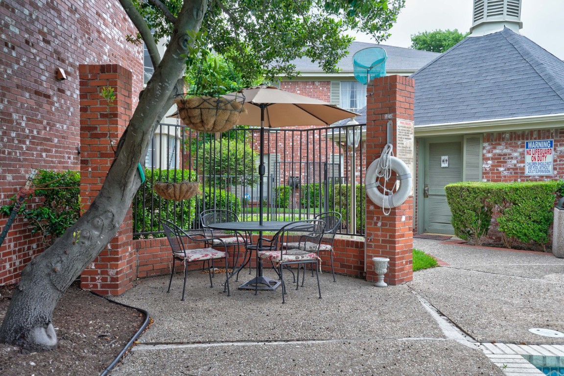 7920 Rockwood Lane, Unit 128 Austin, TX 78757 - Photo 33 of 36 a view of a patio with a table and chairs under an umbrella