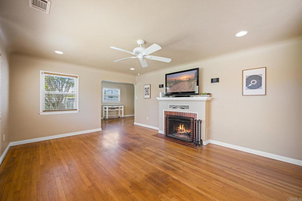 a view of a livingroom with a fireplace a ceiling fan and wooden floor