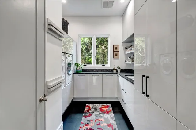 a kitchen with white cabinets and sink