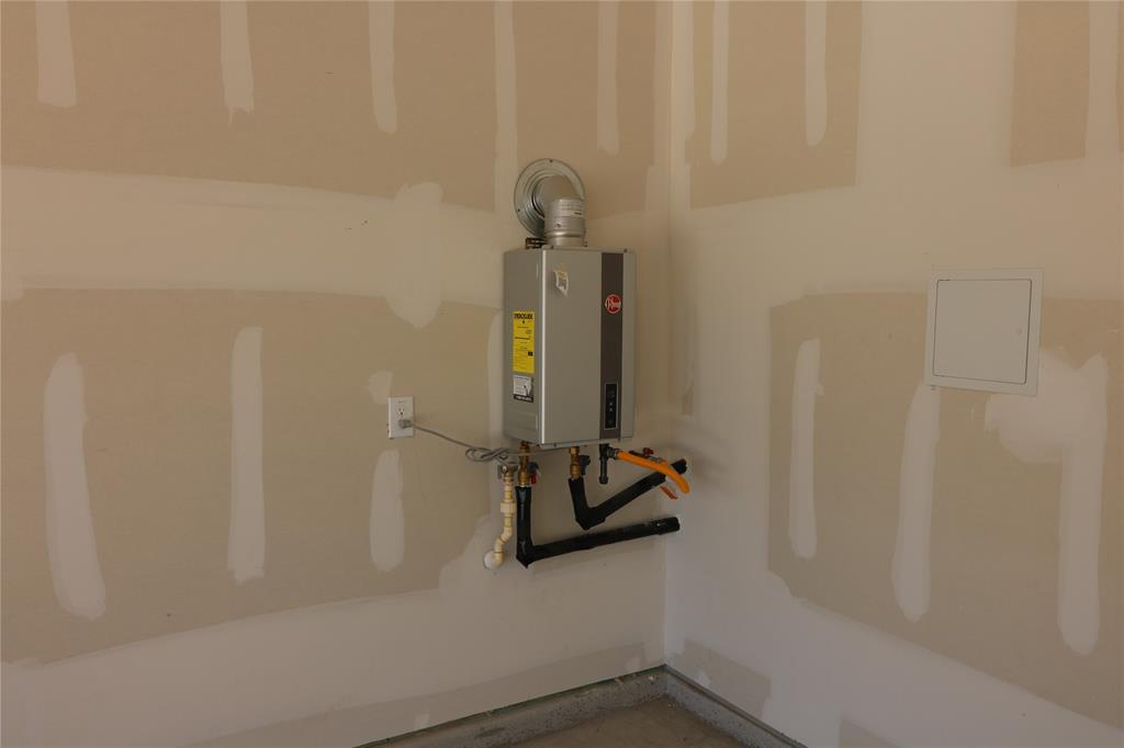 1301 Elliott Road Howe, TX 75459 - Photo 25 of 27 Wall-mounted tankless water heater with visible plumbing and an exhaust vent