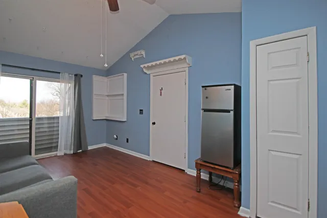 a view of empty room with wooden floor and fan