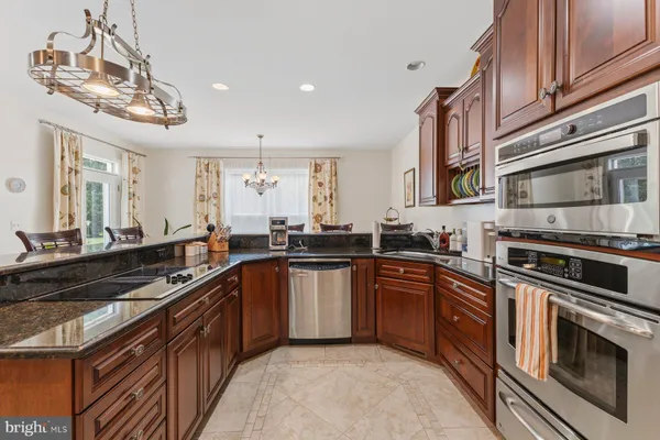 a kitchen with stainless steel appliances granite countertop a stove top oven a sink dishwasher and cabinets with wooden floor