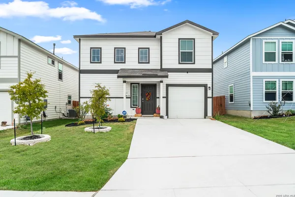a front view of a house with a yard and trees