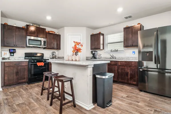 a kitchen with stainless steel appliances a sink a stove a refrigerator cabinets and a dining table