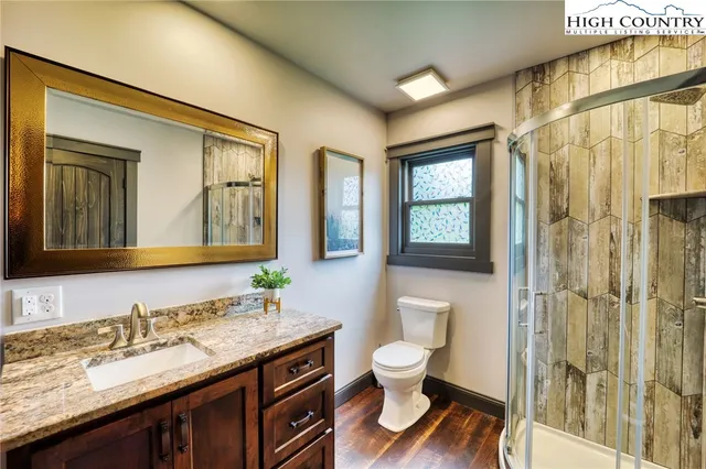 a bathroom with a granite countertop sink toilet a mirror a vanity and shower