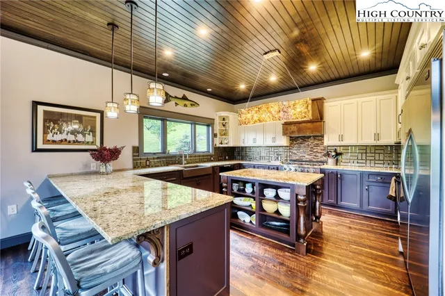 a kitchen with stainless steel appliances granite countertop a table chairs and a refrigerator