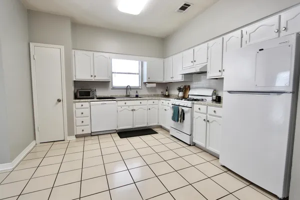 a kitchen with white cabinets a sink dishwasher and a refrigerator