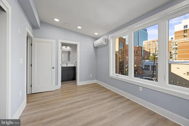 a view of an empty room with a window and wooden floor