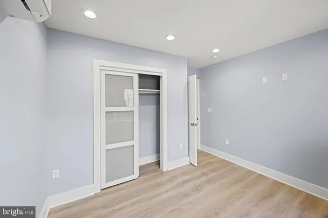 a view of an empty room with wooden floor and closet