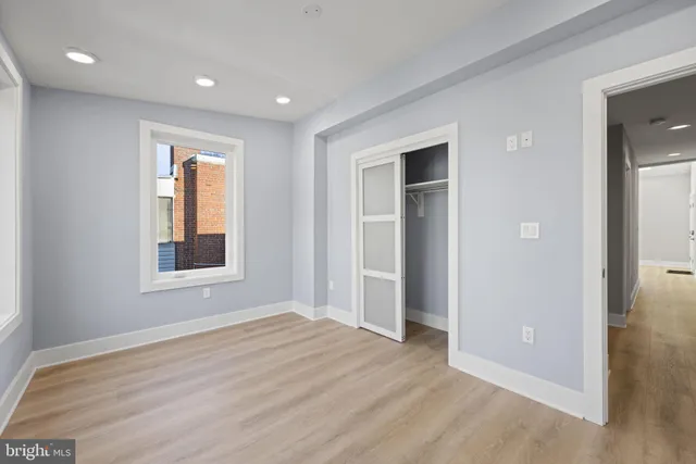 a view of an empty room with wooden floor and window