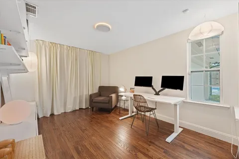 a work room with furniture wooden floor and a window
