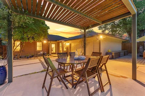 a view of a patio with a table and chairs and floor to ceiling window with wooden fence