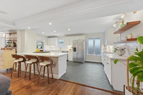 a kitchen with stainless steel appliances granite countertop a table chairs and a refrigerator