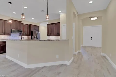 a large white kitchen with a large island oven a stove and a refrigerator with wooden floor