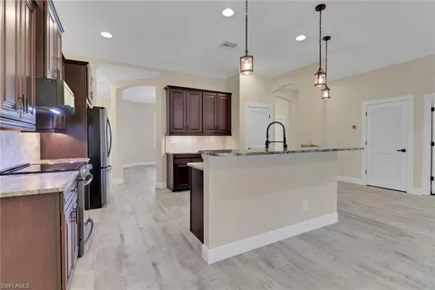 a kitchen with kitchen island granite countertop a sink appliances and cabinets