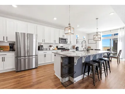 a kitchen with stainless steel appliances granite countertop a refrigerator a stove a sink a dining table and chairs