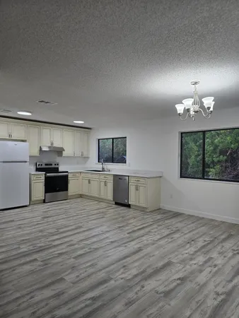 a view of a kitchen with a stove wooden cabinets and a living room
