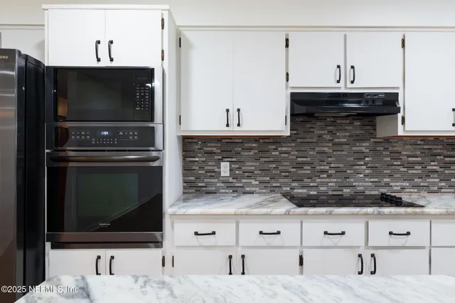 a kitchen with stainless steel appliances kitchen island granite countertop a stove a microwave and white cabinets