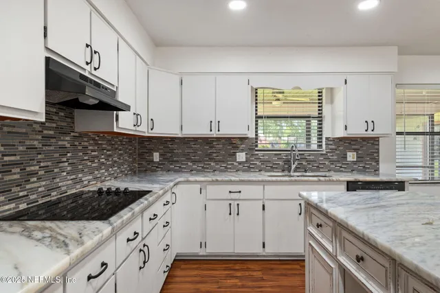 a kitchen with granite countertop a sink a stove and cabinets
