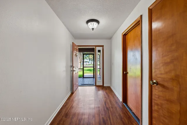 a view of a hallway with wooden floor and a window