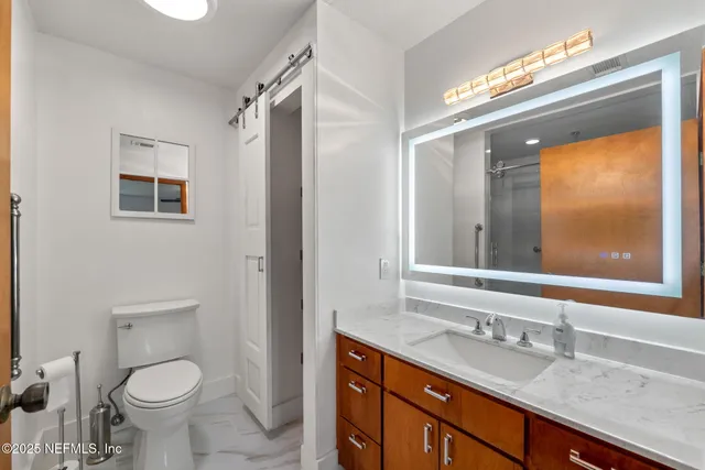 a bathroom with a granite countertop toilet sink and mirror