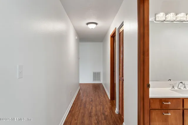 a view of a hallway with wooden floor and a bathroom