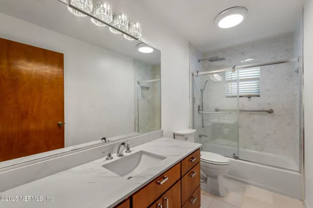 a bathroom with a granite countertop sink a toilet and shower