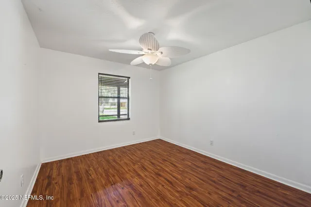 an empty room with a window and a ceiling fan