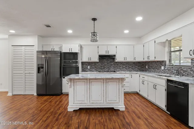 a kitchen with stainless steel appliances granite countertop a refrigerator a sink dishwasher and white cabinets with wooden floor