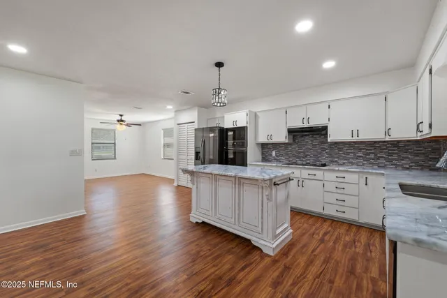 a kitchen with stainless steel appliances granite countertop a stove a sink dishwasher and a oven with white cabinets