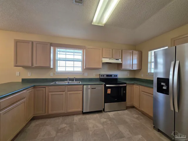 a kitchen with stainless steel appliances granite countertop a refrigerator and a sink